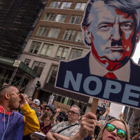 A person shouts next to an image of US President Donald Trump as Nazi dictator Adolf Hitler, as people take part in a protest organized to 'Protect Migrants, Protect the Planet' on April 19, 2025 in New York City. (Adam Gray/Getty Images/AFP)