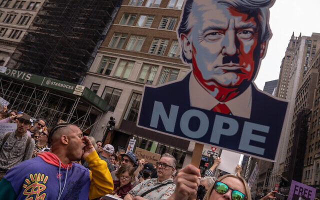A person shouts next to an image of US President Donald Trump as Nazi dictator Adolf Hitler, as people take part in a protest organized to 'Protect Migrants, Protect the Planet' on April 19, 2025 in New York City. (Adam Gray/Getty Images/AFP)