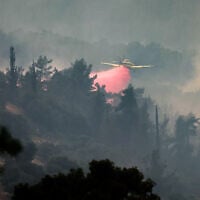 An Air Tractor AT-802AF firefighting aircraft drops flame retardant while trying to extinguish a forest fire near the central Israeli town of Beit Shemesh, near Jerusalem on April 23, 2025. (Ahmad GHARABLI / AFP)