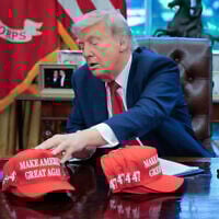 US President Donald Trump adjusts 'Make America Great Again' hats as he prepares to sign executive orders related to education policy, in the Oval Office of the White House in Washington, April 23, 2025. (Chip Somodevilla/Getty Images/AFP)