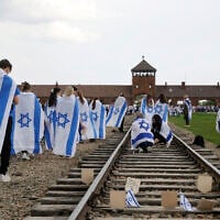Participants with Israel's flag walk along a rail track leading to the gate of the former Auschwitz-Birkenau Nazi death camp in Poland, during the annual March of The Living to honor the victims of the Holocaust on April 24, 2025.  (Photo by Wojtek RADWANSKI / AFP)