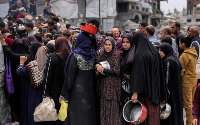 Women queue with pots to receive charity meals from a kitchen in Beit Lahiya in the northern Gaza Strip on April 24, 2025 (Bashar TALEB / AFP)