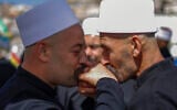 Druze clerics greet each other as they await visitng counterparts from Syria in a bus through a border barrier guarded by Israeli soldiers, near the village of Majdal Shams in the Golan Heights, on April 25, 2025. (Photo by Jalaa MAREY / AFP)