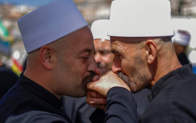 Druze clerics greet each other as they await visitng counterparts from Syria in a bus through a border barrier guarded by Israeli soldiers, near the village of Majdal Shams in the Golan Heights, on April 25, 2025. (Photo by Jalaa MAREY / AFP)