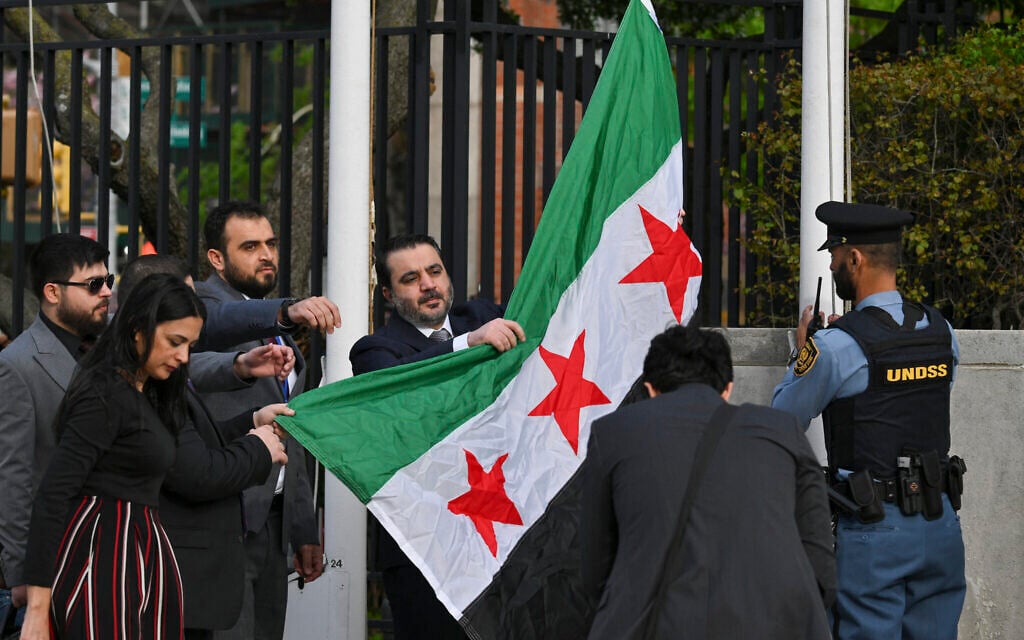 Syrian Foreign Minister Asaad al-Shaibani raises the new Syrian flag during a flag raising ceremony at the United Nations Headquarters in New York on April 25, 2025. (ANGELA WEISS / AFP)