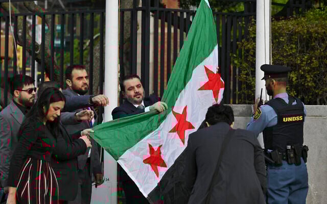Syrian Foreign Minister Asaad al-Shaibani raises the new Syrian flag during a flag raising ceremony at the United Nations Headquarters in New York on April 25, 2025. (ANGELA WEISS / AFP)