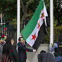 Syrian Foreign Minister Asaad al-Shaibani raises the new Syrian flag during a flag raising ceremony at the United Nations Headquarters in New York on April 25, 2025. (Photo by ANGELA WEISS / AFP)