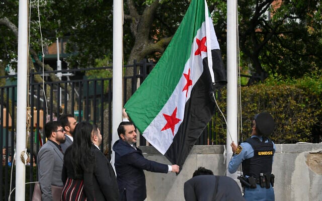 Syrian Foreign Minister Asaad al-Shaibani raises the new Syrian flag during a flag raising ceremony at the United Nations Headquarters in New York on April 25, 2025. (Photo by ANGELA WEISS / AFP)
