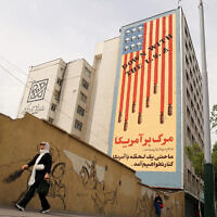 Women walk near a building bearing an anti-US mural with the slogan "Down with the USA" and skulls replacing the stars on the US flag, on Tehran's Karim Khan Zand avenue on April 26, 2025. (ATTA KENARE / AFP)