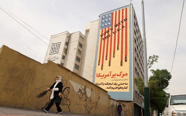 Women walk near a building bearing an anti-US mural with the slogan "Down with the USA" and skulls replacing the stars on the US flag, on Tehran's Karim Khan Zand avenue on April 26, 2025. (ATTA KENARE / AFP)