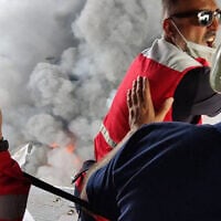 A handout picture provided by the Iranian Red Crescent (RCS) on April 27, 2025, shows members of a rescue team arriving by helicopter at the scene of an explosion that took place a day earlier at the Shahid Rajaee port dock southwest of Bandar Abbas in the Iranian province of Hormozgan (Iranian Red Crescent / AFP)