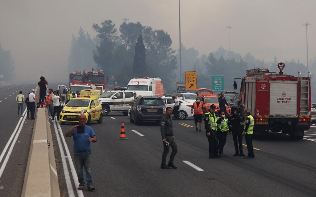 Firefighters and police gather on the highway during a forest fire near the central Israeli town of Bet Shemesh on April 30, 2025. (Photo by Ahmad GHARABLI / AFP)