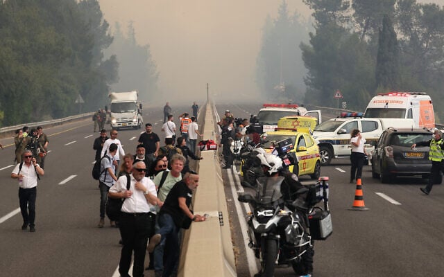 People are evacuated from a highway during a forest fire near the central Israeli town of Bet Shemesh on April 30, 2025. (Photo by Ahmad GHARABLI / AFP)