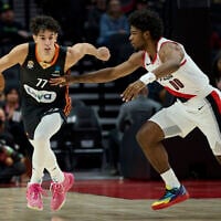 Ratiopharm Ulm guard Ben Saraf, left, dribbles past Portland Trail Blazers guard Scoot Henderson during the first half of a preseason NBA basketball game in Portland, Ore., Wednesday, Oct. 16, 2024. (AP Photo/Craig Mitchelldyer)