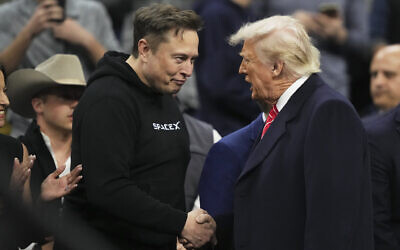 Elon Musk, left, shakes hands with US President Donald Trump at the finals for the NCAA wrestling championship, on March 22, 2025, in Philadelphia, Pennsylvania. (AP Photo/Matt Rourke)