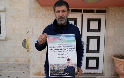 Khalid Ahmad holds a poster of his 17-year-old son, Waleed, who died in an Israeli prison, that reads in Arabic, 'The hero prisoner Martyr, mercy and eternity for our righteous Martyrs,' in the West Bank town of Silwad, northeast of Ramallah March 26, 2025. (Nasser Nasser/AP)