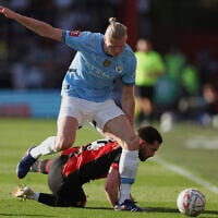 Norwegian soccer player Erling Haaland, top, who plays for Manchester City, duels for the ball with Bournemouth's Lewis Cook during the English FA Cup quarterfinal soccer match between Bournemouth and Manchester City at the Vitality stadium in Bournemouth, England, March 30, 2025. (Ian Walton/AP)