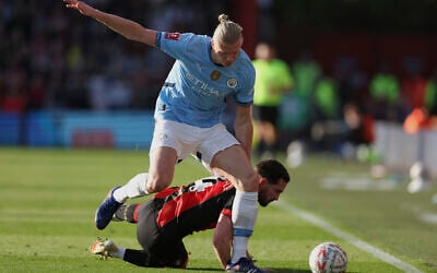 Norwegian soccer player Erling Haaland, top, who plays for Manchester City, duels for the ball with Bournemouth's Lewis Cook during the English FA Cup quarterfinal soccer match between Bournemouth and Manchester City at the Vitality stadium in Bournemouth, England, March 30, 2025. (Ian Walton/AP)