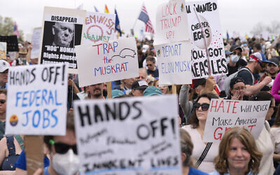 Demonstrators hold up signs during a "Hands Off!" protest against US President Donald Trump at the Washington Monument in Washington, April 5, 2025. (AP/Jose Luis Magana)