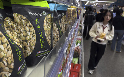 People walk by shelf displaying imported nuts from the United States, at the Hema supermarket, in Beijing, Tuesday, April 8, 2025. (AP Photo/Andy Wong)