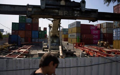 A boy looks at shipping containers in Haifa's port , Israel, Wednesday, April 9, 2025. (AP Photo/Ariel Schalit)