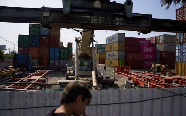 A boy looks at shipping containers in Haifa's port , Israel, Wednesday, April 9, 2025. (AP Photo/Ariel Schalit)