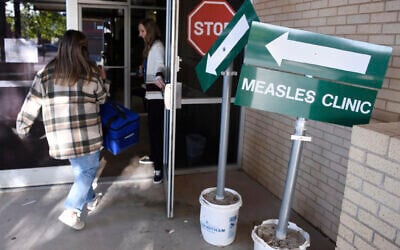 Health department staff members enter the Andrews County Health Department measles clinic carrying doses of the measles, mumps and rubella vaccine, April 8, 2025, in Andrews, Texas. (AP Photo/Annie Rice)
