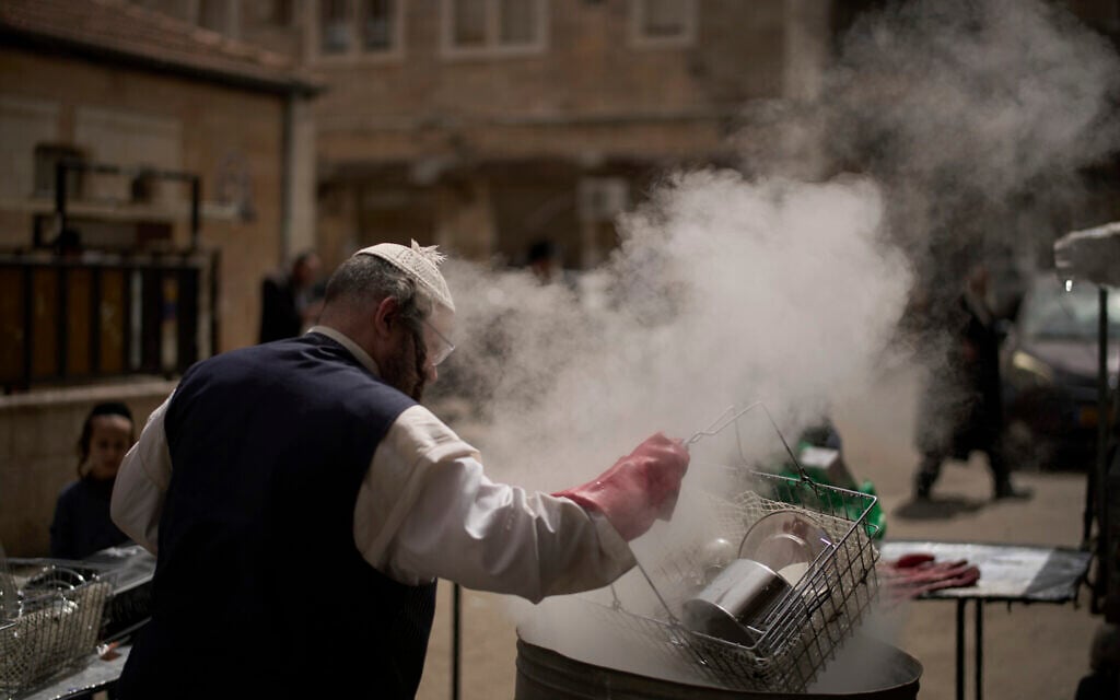 A Jewish man dips utensils in boiling water in preparation for the upcoming holiday of Passover, in the ultra-Orthodox neighborhood of Mea Shearim, in Jerusalem, April 10, 2025. (AP/Leo Correa)