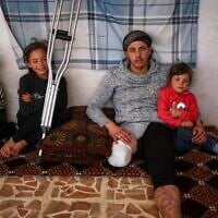 Suleiman Khalil, 21, who lost his leg in a landmine explosion while harvesting olives with his friends in a field, with his siblings from left to right, Sakina, 8, Nahla, 9, and Aya, 5, at his home in the village of Qaminas, east of Idlib, Syria, April 9, 2025. (Ghaith Alsayed/AP)