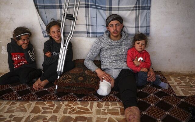 Suleiman Khalil, 21, who lost his leg in a landmine explosion while harvesting olives with his friends in a field, with his siblings from left to right, Sakina, 8, Nahla, 9, and Aya, 5, at his home in the village of Qaminas, east of Idlib, Syria, April 9, 2025. (Ghaith Alsayed/AP)