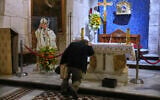 A man prays beside a photo of the late Pope Francis after the news of his death at age 88, at the Church of the Holy Sepulcher, the site where according to tradition Jesus was crucified and buried, in Jerusalem's Old City, on April 21, 2025. (AP Photo/Ohad Zwigenberg)