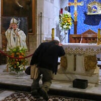 A man prays beside a photo of the late Pope Francis after the news of his death at age 88, at the Church of the Holy Sepulcher, the site where according to tradition Jesus was crucified and buried, in Jerusalem's Old City, on April 21, 2025. (AP Photo/Ohad Zwigenberg)