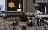 People walk next to a billboard showing a yellow Star of David that reads "Jude," Jew in German, resembling the one Jews were forced to wear in Nazi Germany, during the annual Holocaust Remembrance Day in Ramat Gan, April 24, 2025. (AP Photo/Oded Balilty)