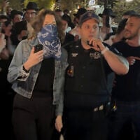 This image taken from video shows a woman and a police officer as they are pursued by a group of Orthodox Jewish men in the Crown Heights section of Brooklyn, New York, following an anti-Israel protest outside a synagogue on April 24, 2025. (AP Photo)