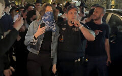 This image taken from video shows a woman and a police officer as they are pursued by a group of Orthodox Jewish men in the Crown Heights section of Brooklyn, New York, following an anti-Israel protest outside a synagogue on April 24, 2025. (AP Photo)