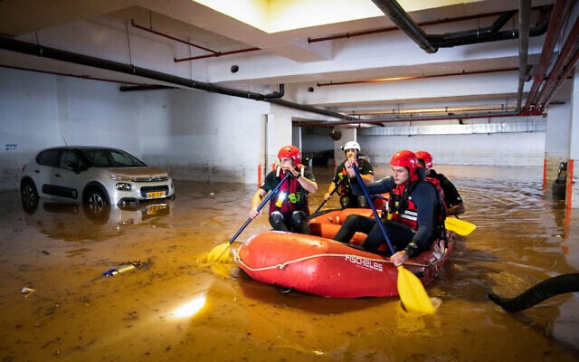 Israeli firefighters search for people at a parking lot that was flooded following heavy rainfall in Ness Ziona, November 21, 2020. (Yossi Aloni/Flash90)