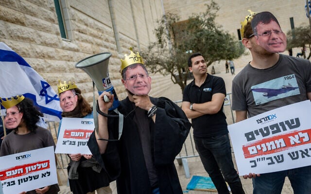 Anti-High Court protesters wear masks of Chief Justice Isaam Amit as he and two other judges hear petitions against the ouster of Shin Bet chief Ronen Bar, in Jerusalem, April 8, 2025. (Yonatan Sindel/Flash90 Anti-High Court protesters wear masks of Chief Justice Isaam Amit as he and two other judges hear petitions against the ouster of Shin Bet chief Ronen Bar, in Jerusalem, April 8, 2025. (Yonatan Sindel/Flash90