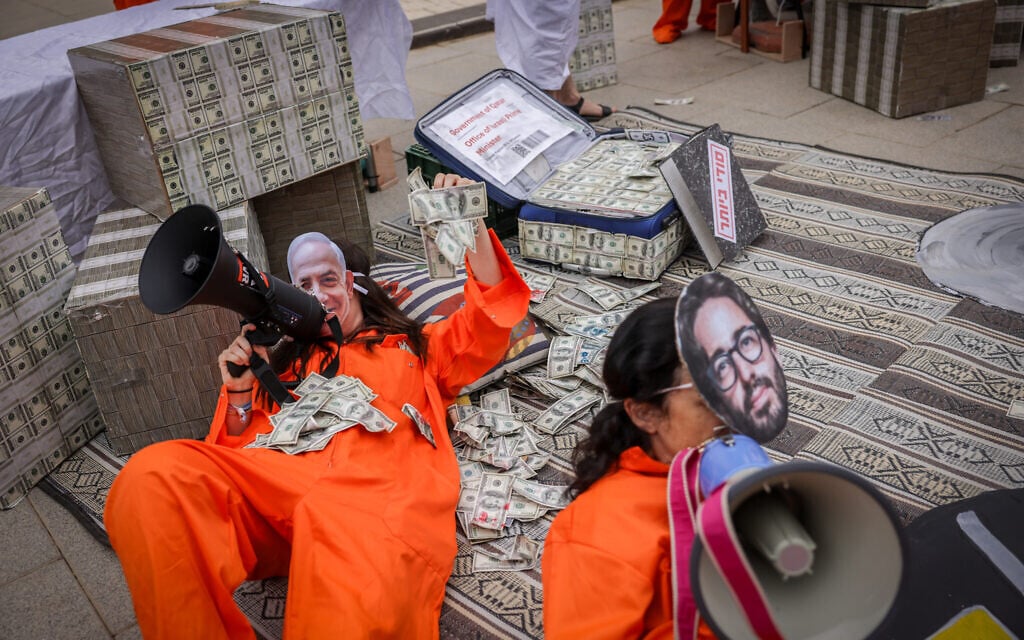 Israelis protest against Prime Minister Benjamin Netanyahu with imagery referring to the so-called Qatargate scandal and the investigation into his senior aides, outside the Tel Aviv District Court as the premier arrives to testify in his ongoing criminal trial, April 9, 2025. (Miriam Alster/Flash90)