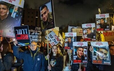 Protesters, led by family members of people held hostage in Gaza, hold placards showing the face of hostage Edan Alexander, near the home of Strategic Affairs Minister Ron Dermer in Jerusalem, on April 13, 2025. (Chaim Goldberg/Flash90)