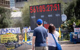 Visitors look on as a clock counts the time since hostages were taken on October 7, 2023, at Hostages Square in Tel Aviv, April 20, 2025. (Miriam Alster/ FLASH90)