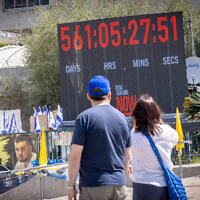 Visitors look on as a clock counts the time since hostages were taken on October 7, 2023, at Hostages Square in Tel Aviv, April 20, 2025. (Miriam Alster/ FLASH90)