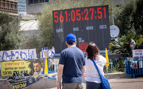 Visitors look on as a clock counts the time since hostages were taken on October 7, 2023, at Hostages Square in Tel Aviv, April 20, 2025. (Miriam Alster/ FLASH90)
