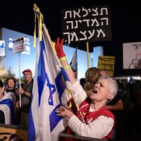 A protest against Prime Minister Benjamin Netanyahu and in support of Shin Bet chief Ronen Bar, as a protestor carries a sign that says, 'Save the country from itself,'  at Habima Square, April 21, 2025 (Photo by Avshalom Sassoni//Flash90)
