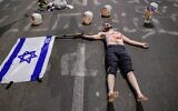 A display of masks bearing Prime Minister Benjamin Netanyahu's face surrounding a protester wearing faux-bloody bandages at an anti-government demonstration in Tel Aviv, April 26, 2025. (Tomer Neuberg/Flash90)