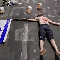 A display of masks bearing Prime Minister Benjamin Netanyahu's face surrounding a protester wearing faux-bloody bandages at an anti-government demonstration in Tel Aviv, April 26, 2025. (Tomer Neuberg/Flash90)