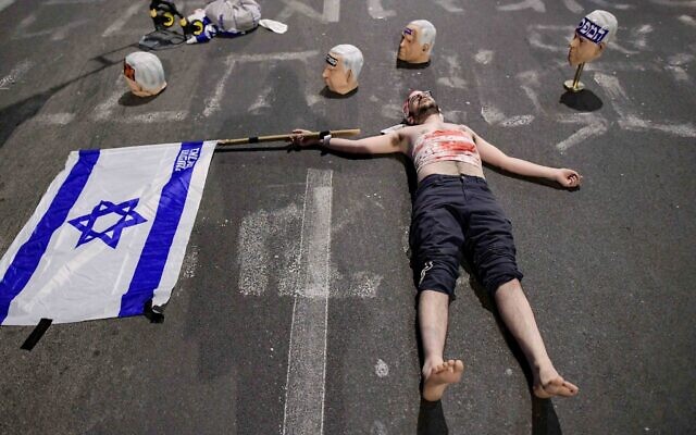A display of masks bearing Prime Minister Benjamin Netanyahu's face surrounding a protester wearing faux-bloody bandages at an anti-government demonstration in Tel Aviv, April 26, 2025. (Tomer Neuberg/Flash90) A display of masks bearing Prime Minister Benjamin Netanyahu's face surrounding a protester wearing faux-bloody bandages at an anti-government demonstration in Tel Aviv, April 26, 2025. (Tomer Neuberg/Flash90)