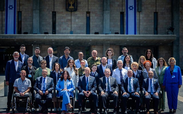 Most of this year's Independence Day torch-lighters pose for a photo outside the Knesset with Knesset Speaker Amir Ohana and Transportation Minister Miri Regev, April 28, 2025. (Yonatan Sindel/Flash90)