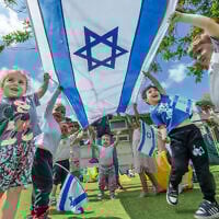Illustrative: Children play with Israeli flags ahead of Israel's 77th Independence Day at a kindergarten in Moshav Yashresh in central Israel, April 29, 2025. (Yossi Aloni/Flash90)