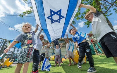 Illustrative: Children play with Israeli flags ahead of Israel's 77th Independence Day at a kindergarten in Moshav Yashresh in central Israel, April 29, 2025. (Yossi Aloni/Flash90)