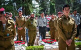 People stand still as a two-minute siren sounded across Israel, marking Memorial Day at Mount Herzl Military Cemetery in Jerusalem on April 30, 2025. (Arie Leib Abrams/Flash90)